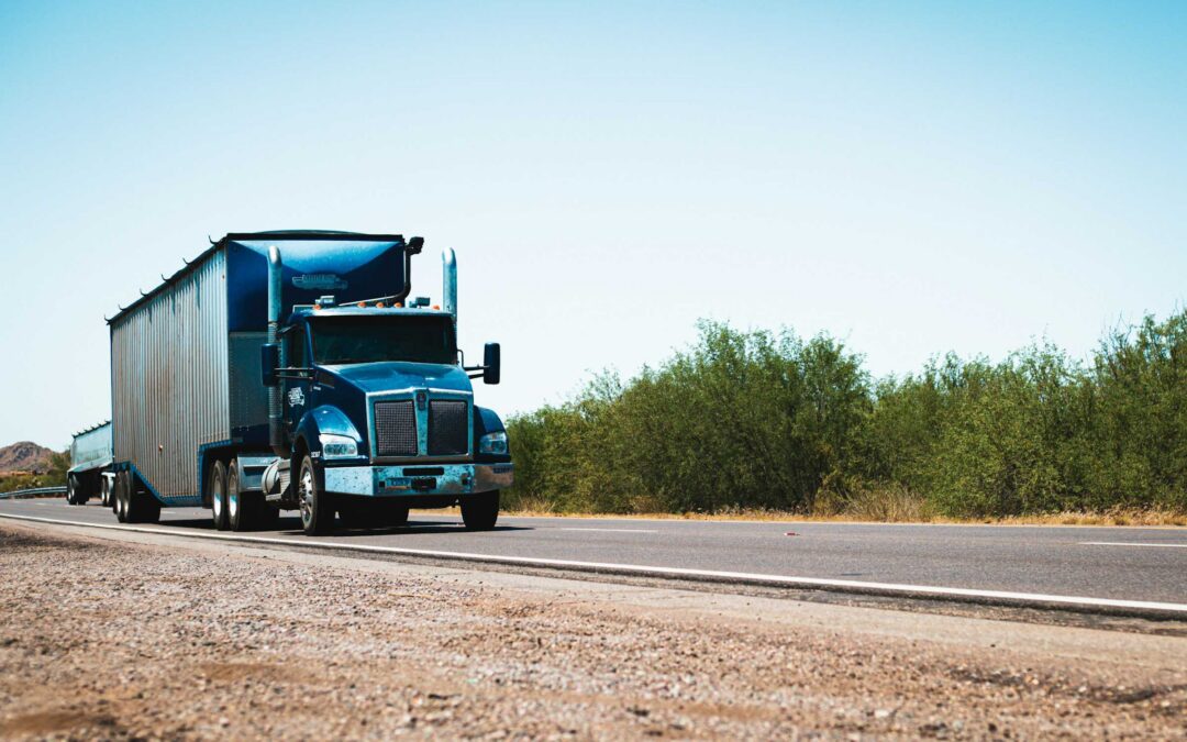 A blue semi-truck drives along a sunny - https://www.insfusa.com/