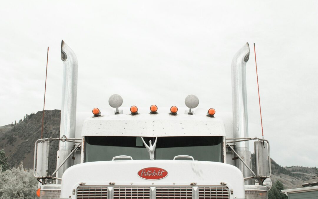 Front view of a white semi-truck with chrome exhaust pipes and red emblem - https://www.insfusa.com/